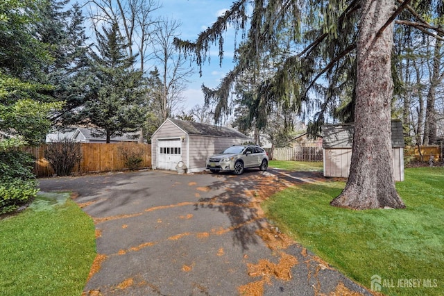 exterior space featuring aphalt driveway, fence, and a storage unit