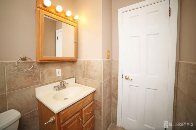 bathroom featuring tile walls, vanity, and toilet