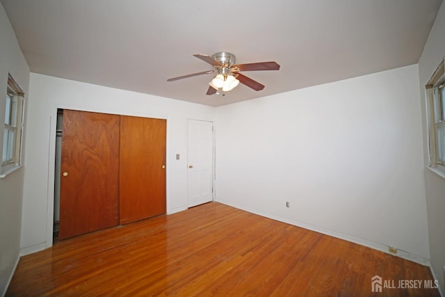 unfurnished bedroom featuring ceiling fan, a closet, and hardwood / wood-style floors