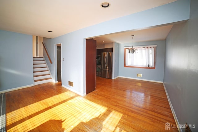 empty room featuring hardwood / wood-style floors and a notable chandelier