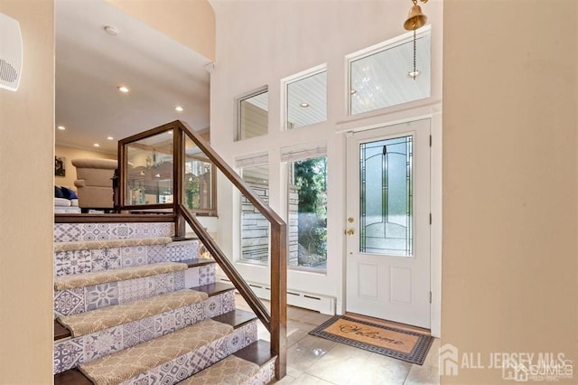 entryway featuring light tile patterned flooring, a high ceiling, and a baseboard heating unit