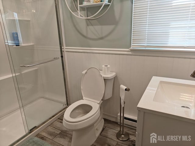 full bathroom with toilet, a shower stall, a baseboard heating unit, and wood finished floors