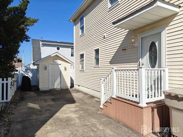 view of side of home featuring an outbuilding, a storage shed, and fence