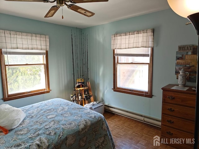 bedroom featuring a baseboard heating unit, parquet flooring, and ceiling fan