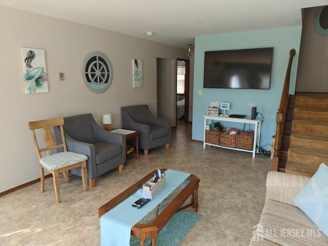 living area featuring baseboards and stairs