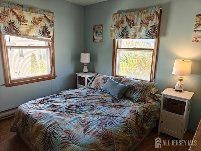 bedroom with a baseboard heating unit and dark parquet flooring