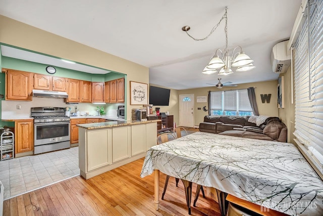 30 Falmouth Rd, Iselin, NJ 08830 - kitchen with stainless steel gas stove, under cabinet range hood, a chandelier, light wood finished floors, and open floor plan