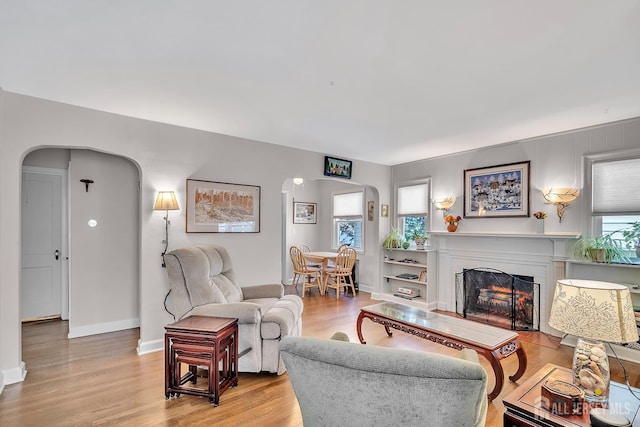 436 2nd St, Dunellen, NJ 08812 - living room featuring arched walkways, light wood-style flooring, and a warm lit fireplace