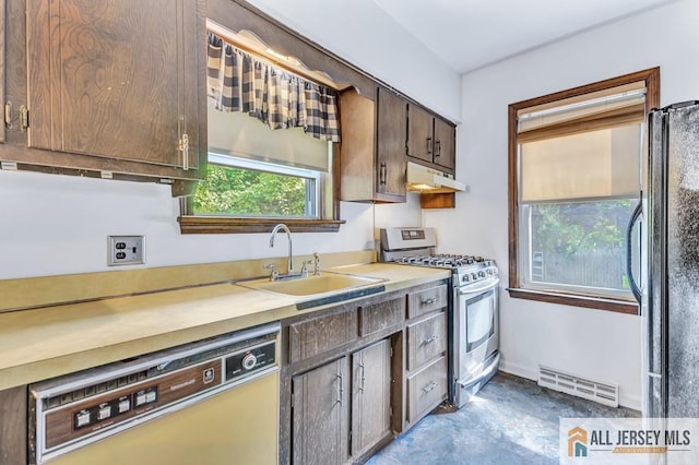 kitchen featuring black refrigerator, dishwasher, sink, gas range, and dark brown cabinets