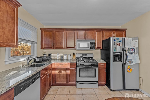 kitchen featuring light tile patterned flooring, light stone countertops, stainless steel appliances, and sink