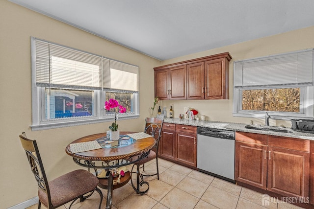 kitchen with light tile patterned floors, sink, stainless steel dishwasher, and light stone countertops