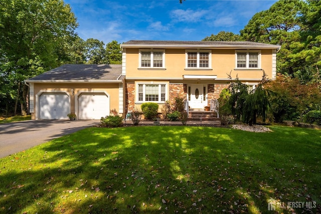 colonial-style house featuring brick siding, an attached garage, a front yard, stucco siding, and driveway