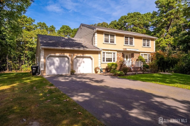 colonial house with stucco siding, an attached garage, driveway, and a front yard