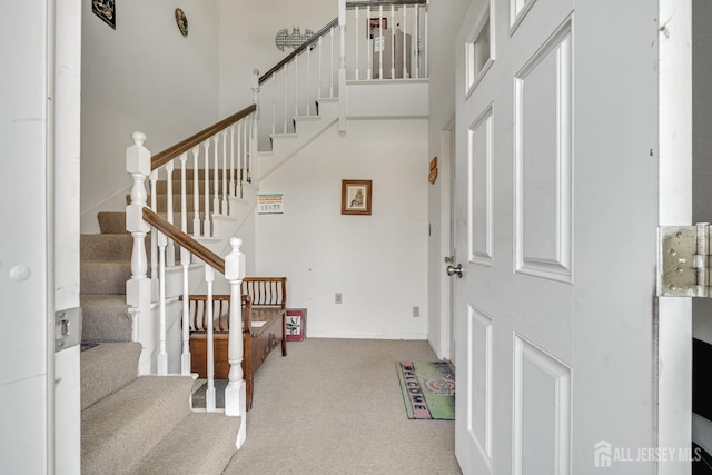 carpeted entryway featuring a towering ceiling