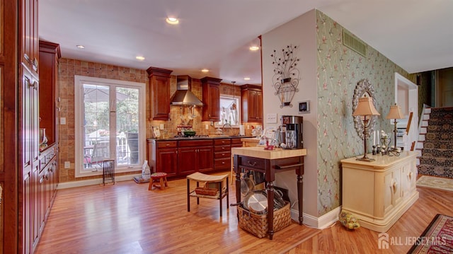 3 Feathertree Ct, Howell, NJ 07731 - kitchen featuring wall chimney range hood, light wood-style flooring, dark brown cabinets, wallpapered walls, and decorative backsplash
