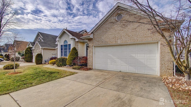 view of front facade with a front lawn, brick siding, an attached garage, and driveway