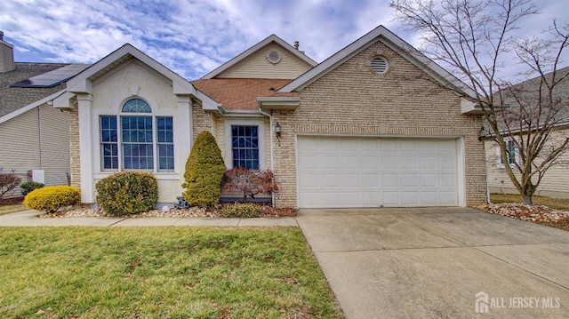 view of front of property featuring brick siding, an attached garage, driveway, and a front yard