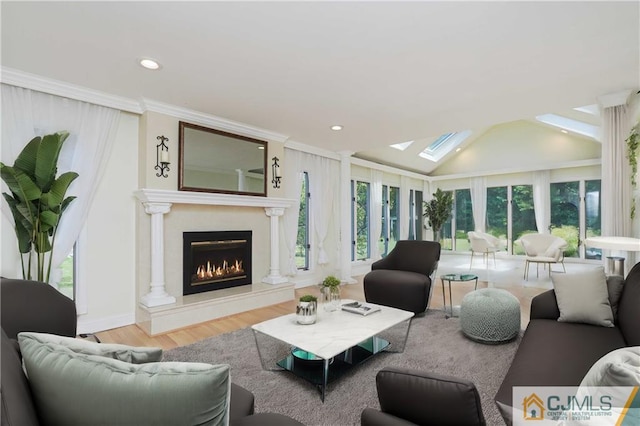 living area with vaulted ceiling with skylight, wood finished floors, crown molding, a fireplace, and recessed lighting