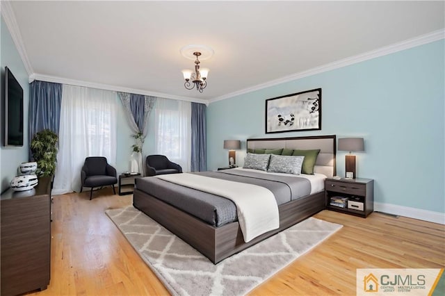 bedroom with light wood-style floors, ornamental molding, baseboards, and an inviting chandelier