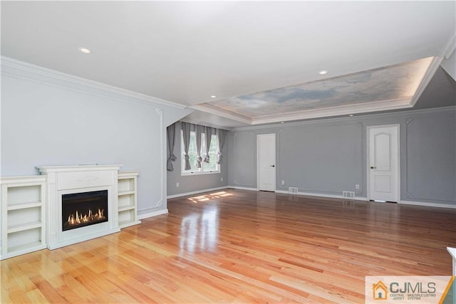 unfurnished living room featuring ornamental molding, a lit fireplace, baseboards, and wood finished floors