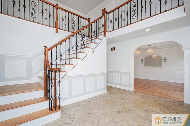 stairway with arched walkways, stone finish floor, recessed lighting, and a decorative wall