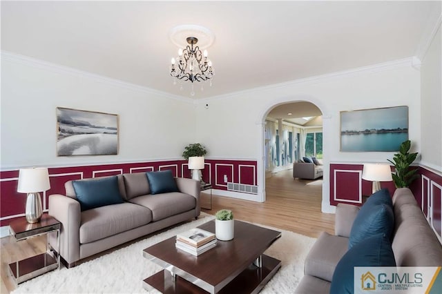 living area with visible vents, arched walkways, ornamental molding, wood finished floors, and a chandelier