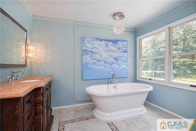 full bathroom with a freestanding bath, vanity, and baseboards