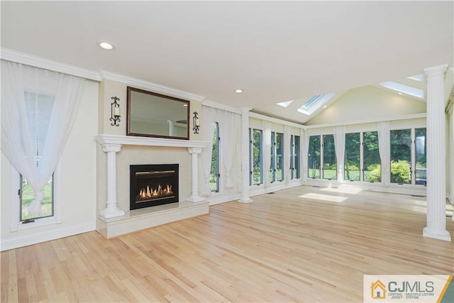 unfurnished living room featuring lofted ceiling, wood finished floors, a high end fireplace, and ornate columns