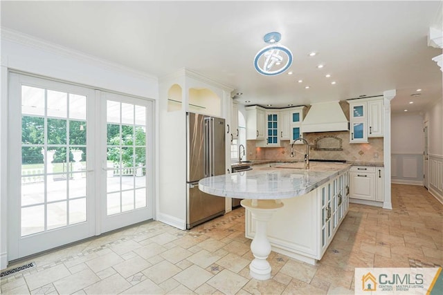 kitchen featuring stainless steel appliances, visible vents, custom exhaust hood, decorative backsplash, and stone finish floor