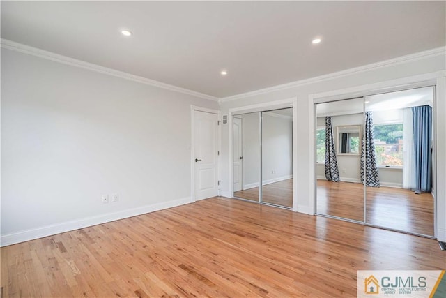 unfurnished bedroom with ornamental molding, baseboards, light wood finished floors, and two closets