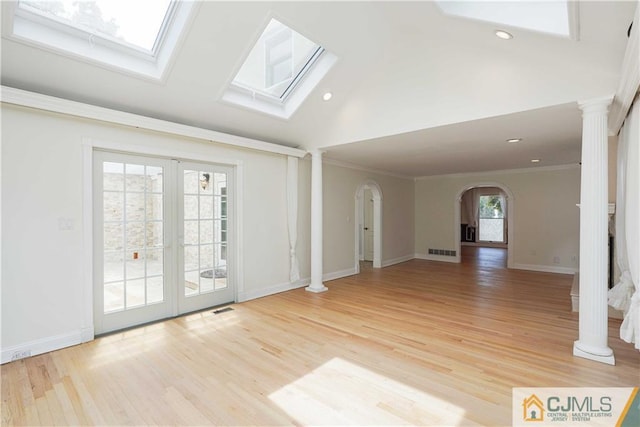 unfurnished living room featuring arched walkways, french doors, decorative columns, visible vents, and ornamental molding