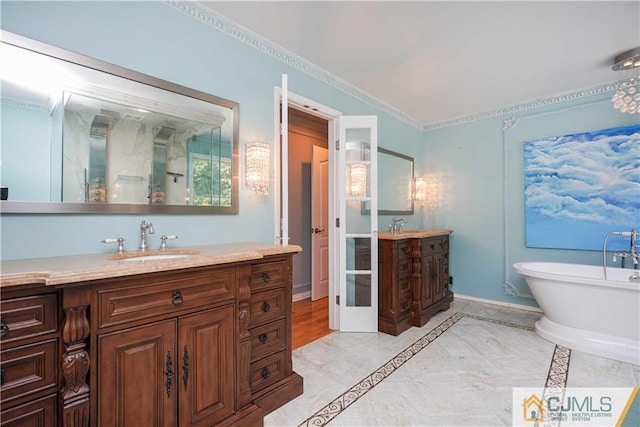 full bath featuring a freestanding tub, vanity, and baseboards