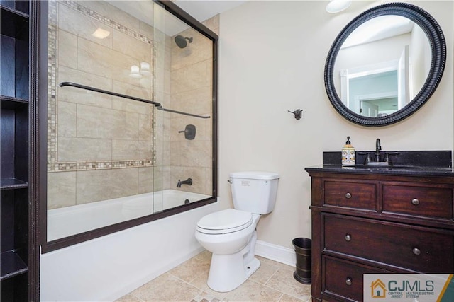 bathroom featuring tile patterned flooring, toilet, vanity, baseboards, and combined bath / shower with glass door