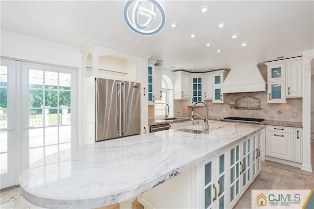 kitchen featuring stainless steel appliances, custom range hood, a sink, and backsplash