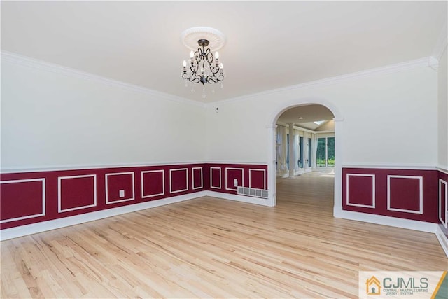 unfurnished room with arched walkways, visible vents, a notable chandelier, and wood finished floors