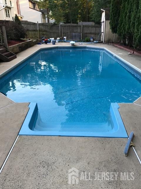view of pool featuring a fenced in pool, a fenced backyard, a diving board, and a patio area