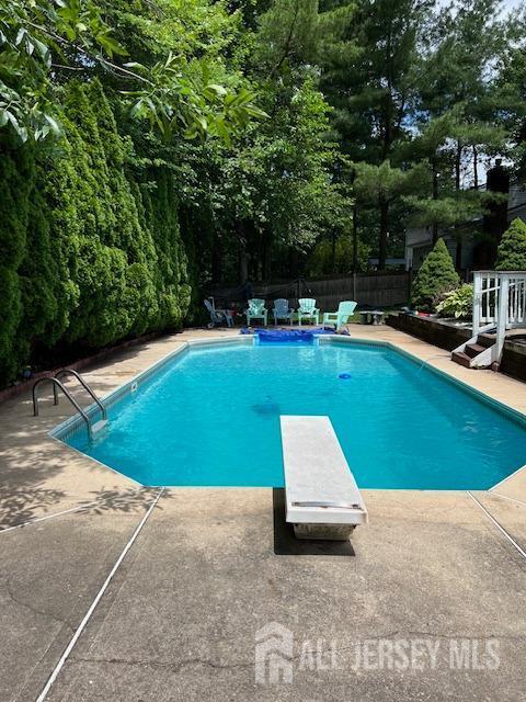 view of pool featuring a patio area, a fenced in pool, fence, and a diving board