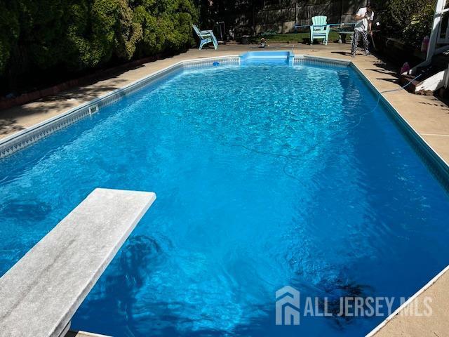 pool with a diving board and a patio area