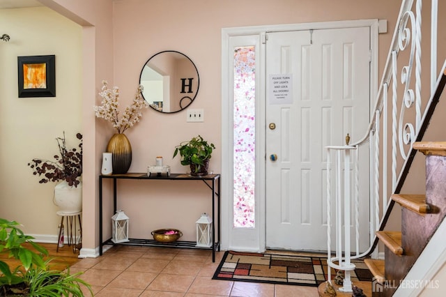 entrance foyer featuring baseboards, stairway, and tile patterned floors