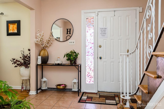tiled entrance foyer featuring baseboards and stairs