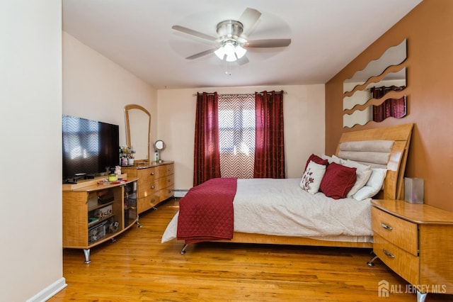 bedroom featuring a baseboard radiator, a ceiling fan, and wood finished floors