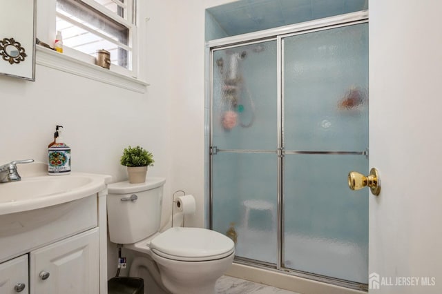 bathroom featuring marble finish floor, toilet, a stall shower, and vanity