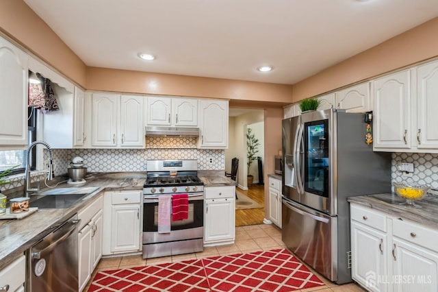 kitchen with decorative backsplash, appliances with stainless steel finishes, under cabinet range hood, white cabinetry, and a sink