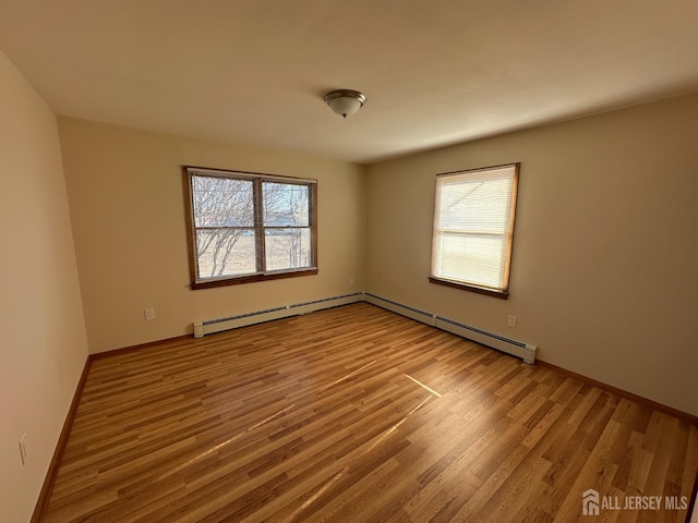 spare room with plenty of natural light, a baseboard radiator, and wood finished floors