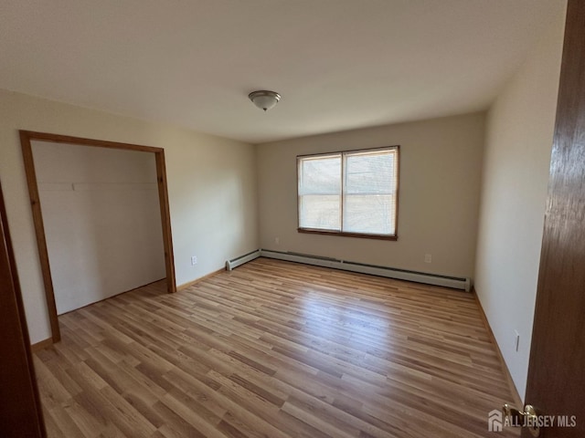 unfurnished bedroom with a baseboard radiator and wood finished floors