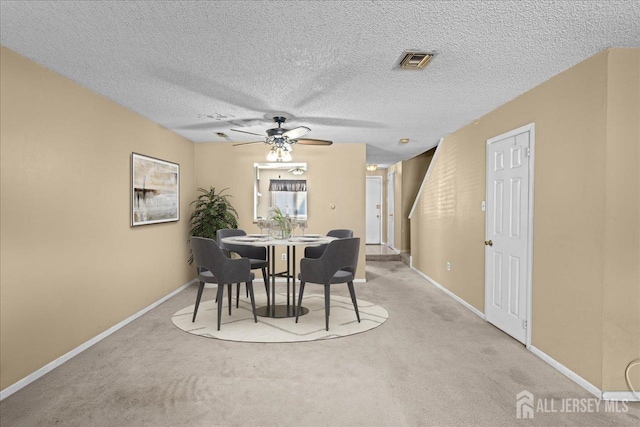 dining area with a textured ceiling, ceiling fan, and light carpet