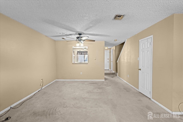 spare room with a textured ceiling, light carpet, and ceiling fan