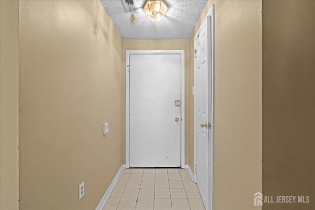 entryway with a textured ceiling and light tile patterned floors