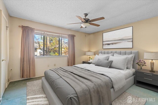 carpeted bedroom with ceiling fan and a textured ceiling