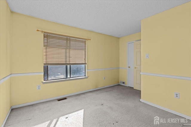 carpeted spare room with a textured ceiling